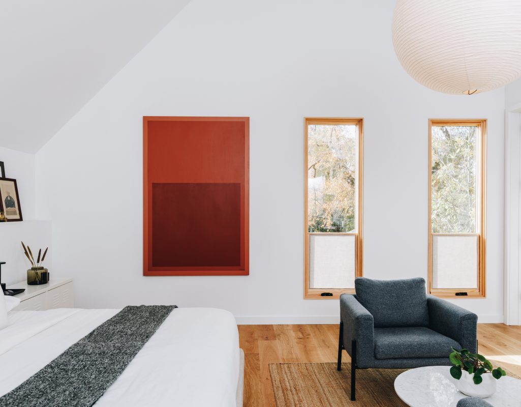 Bright bedroom with a red color-field painting and oak-framed windows