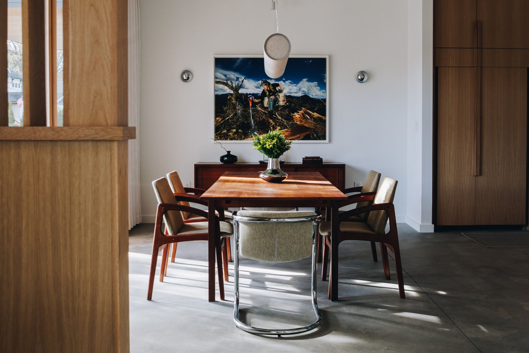 Teak dining table in a sunlit room with concrete floors