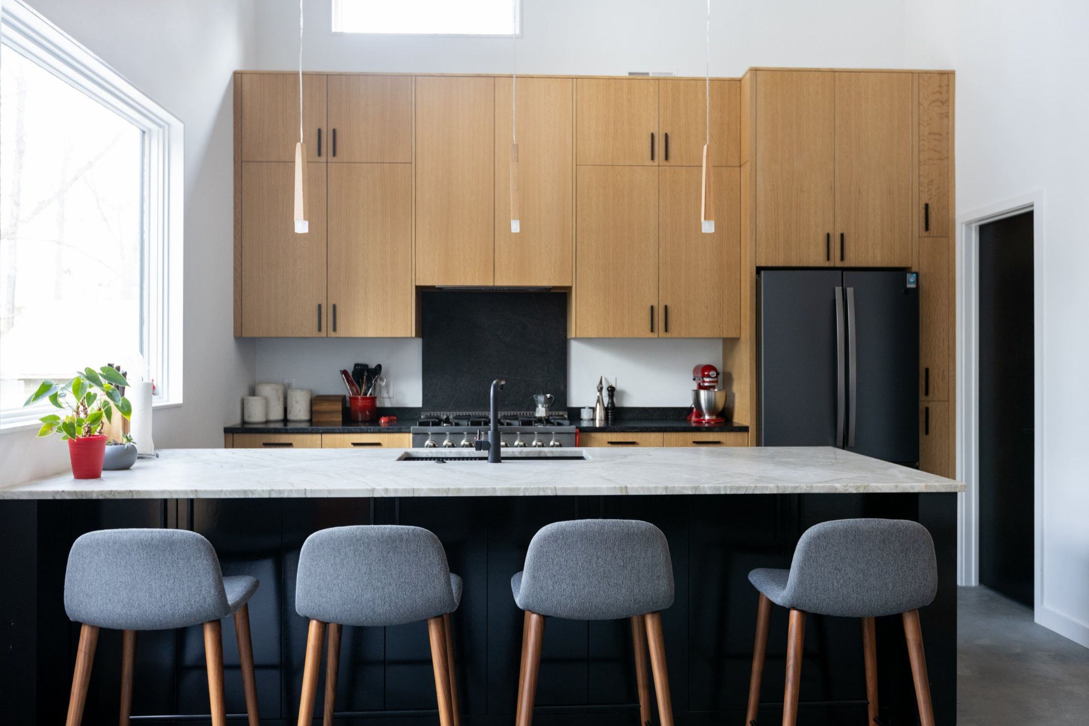 Oak kitchen with a black island and gray stools