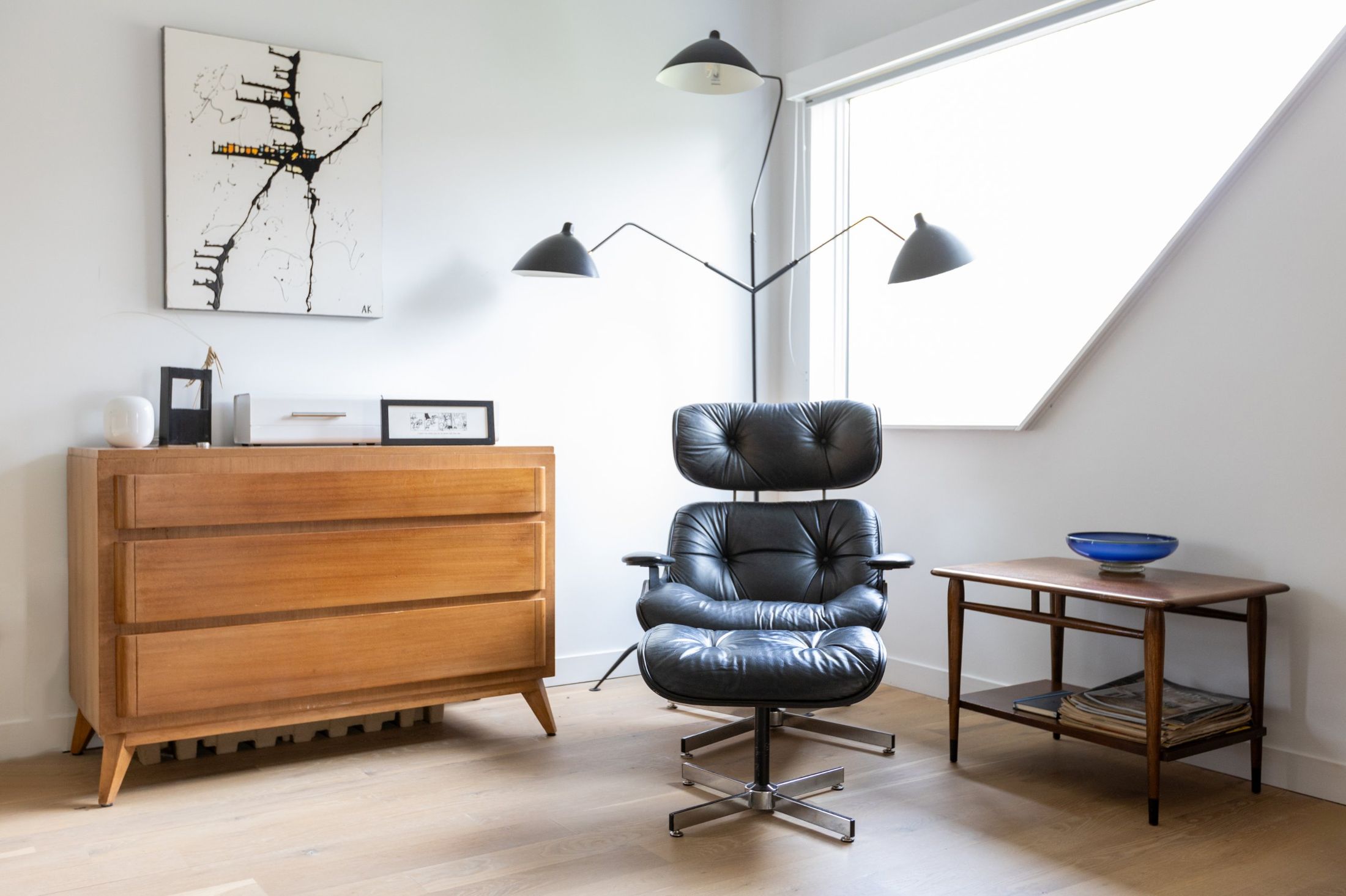 Black leather lounge chair and ottoman under a three-arm floor lamp