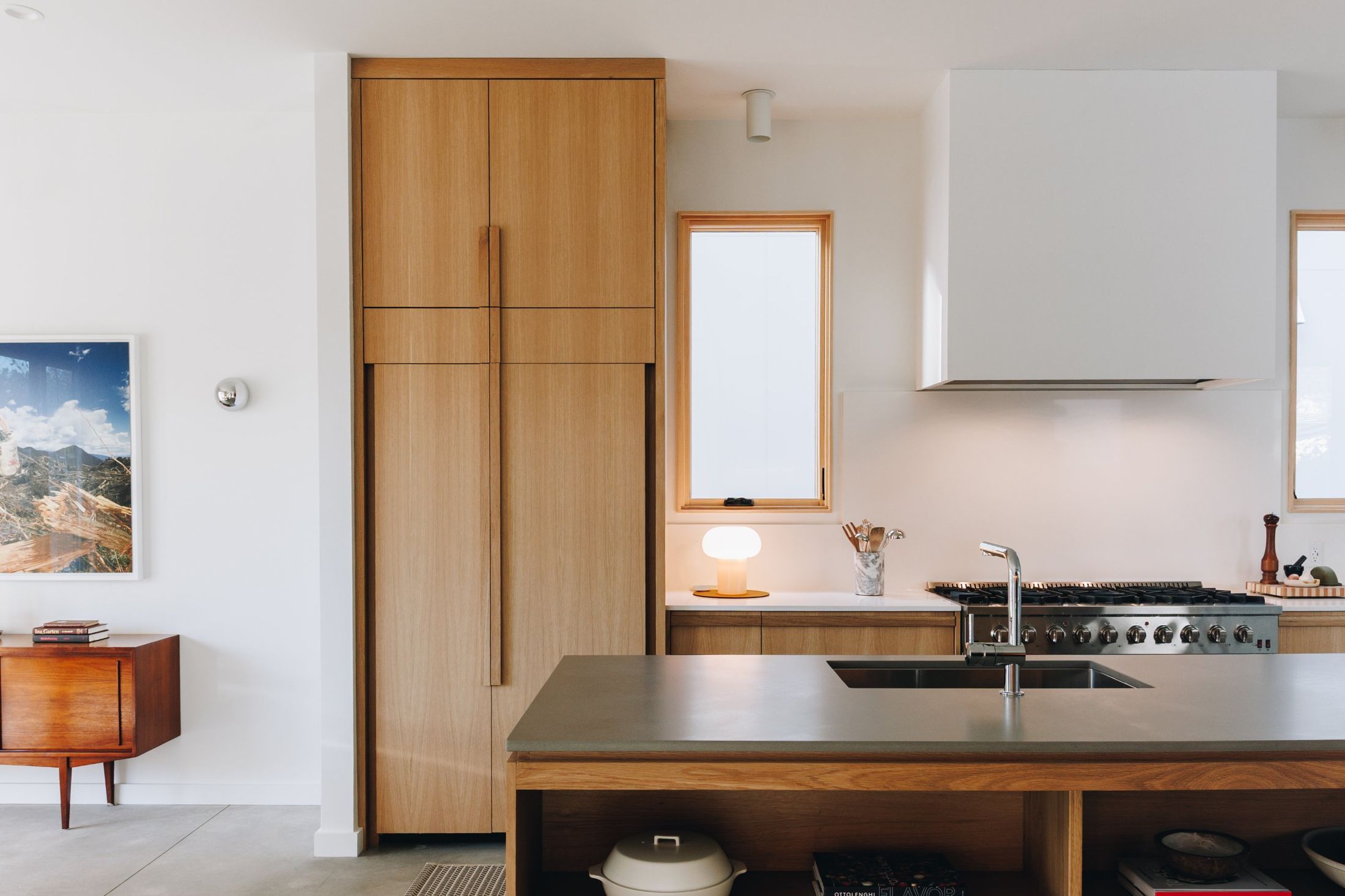 Rift oak pantry wall beside a white range hood and concrete island