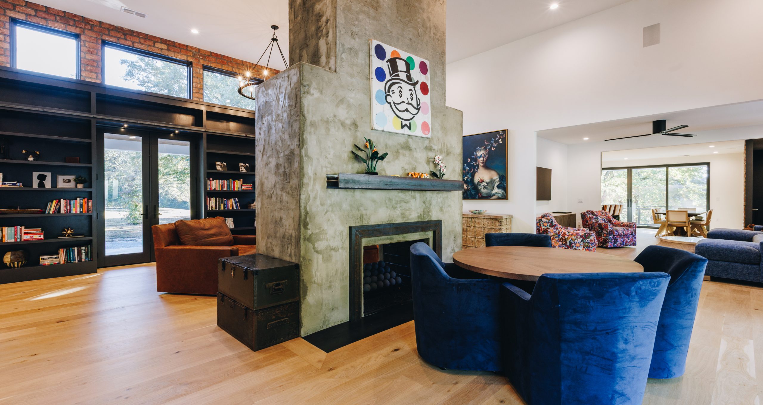Shaftesbury living room with a plaster fireplace, blue velvet chairs and a library wall