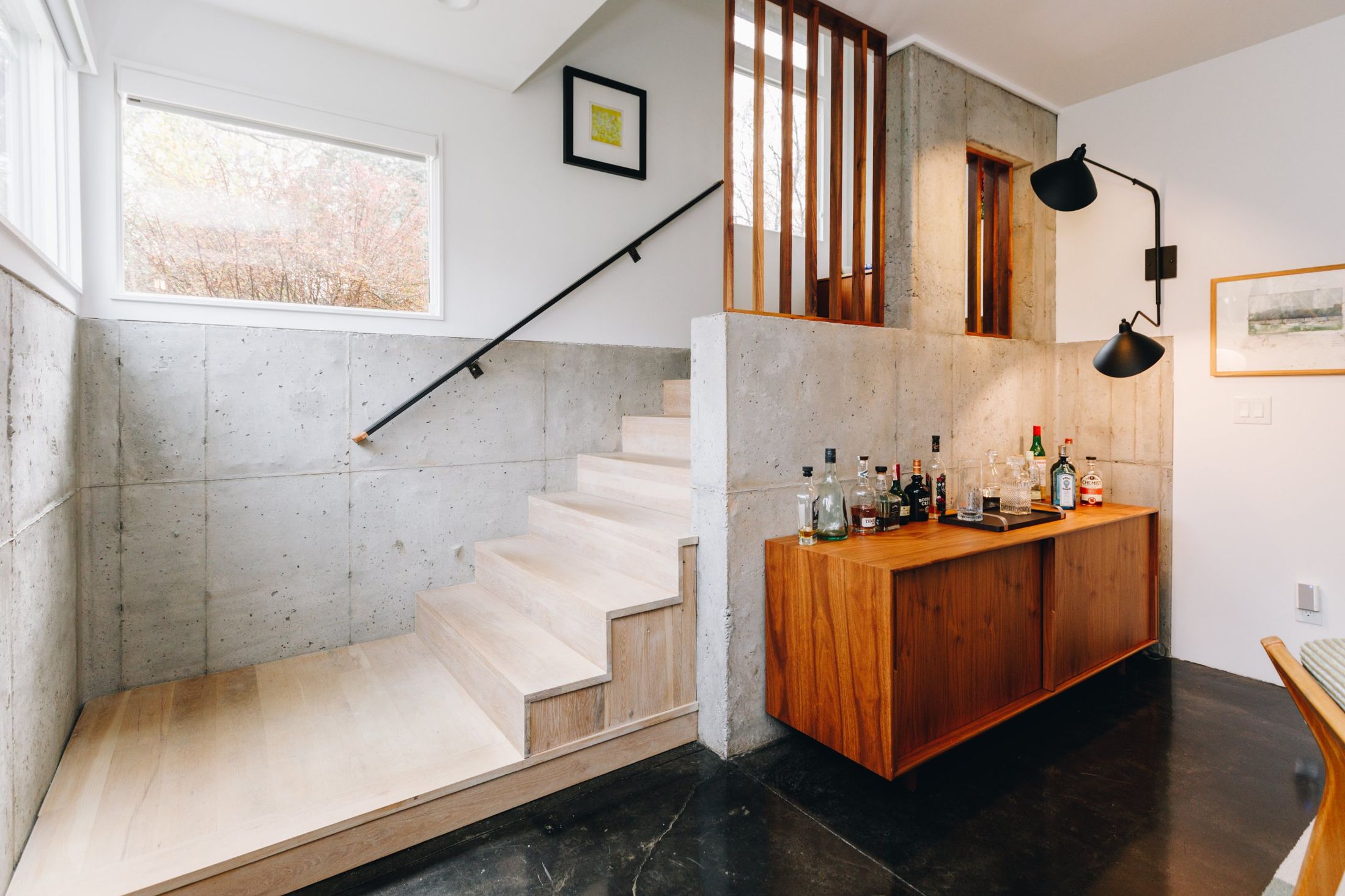 White oak stair against board-formed concrete with a walnut bar cabinet