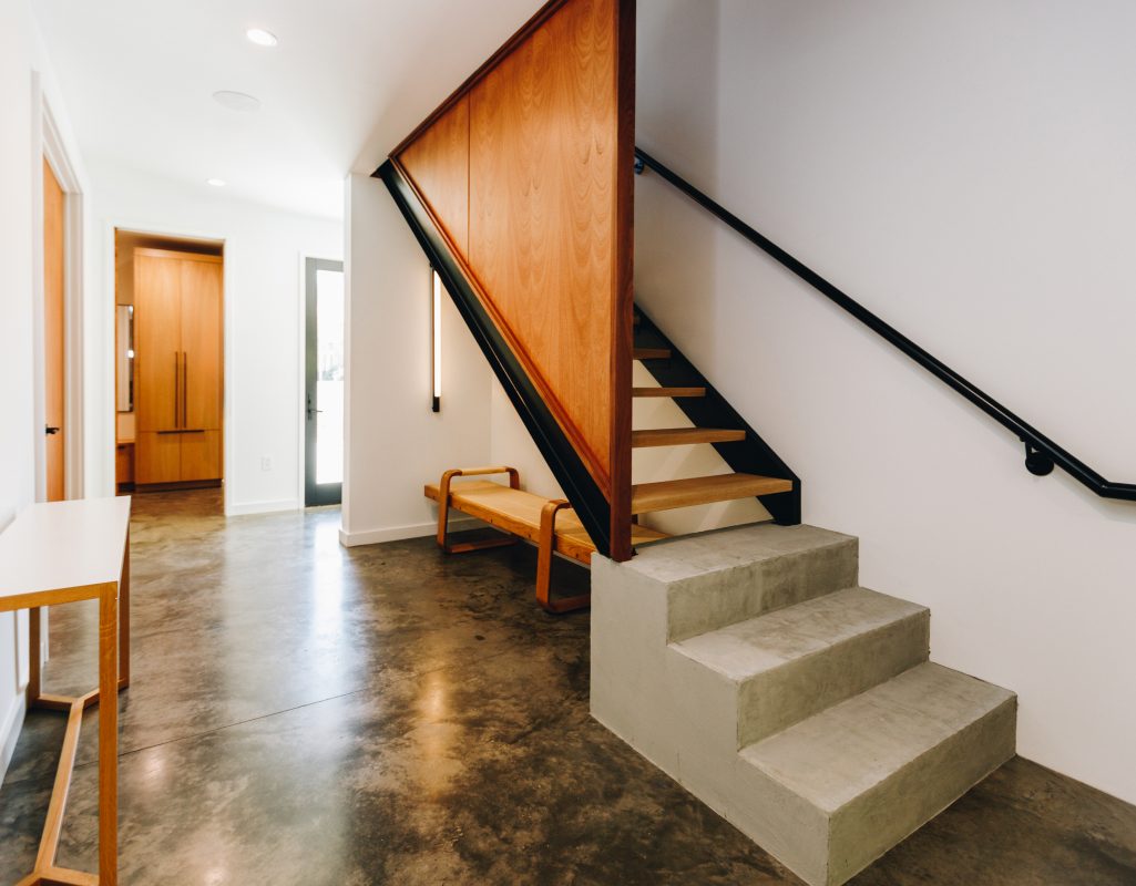 Floating steel stair with an oak panel above board-formed concrete steps