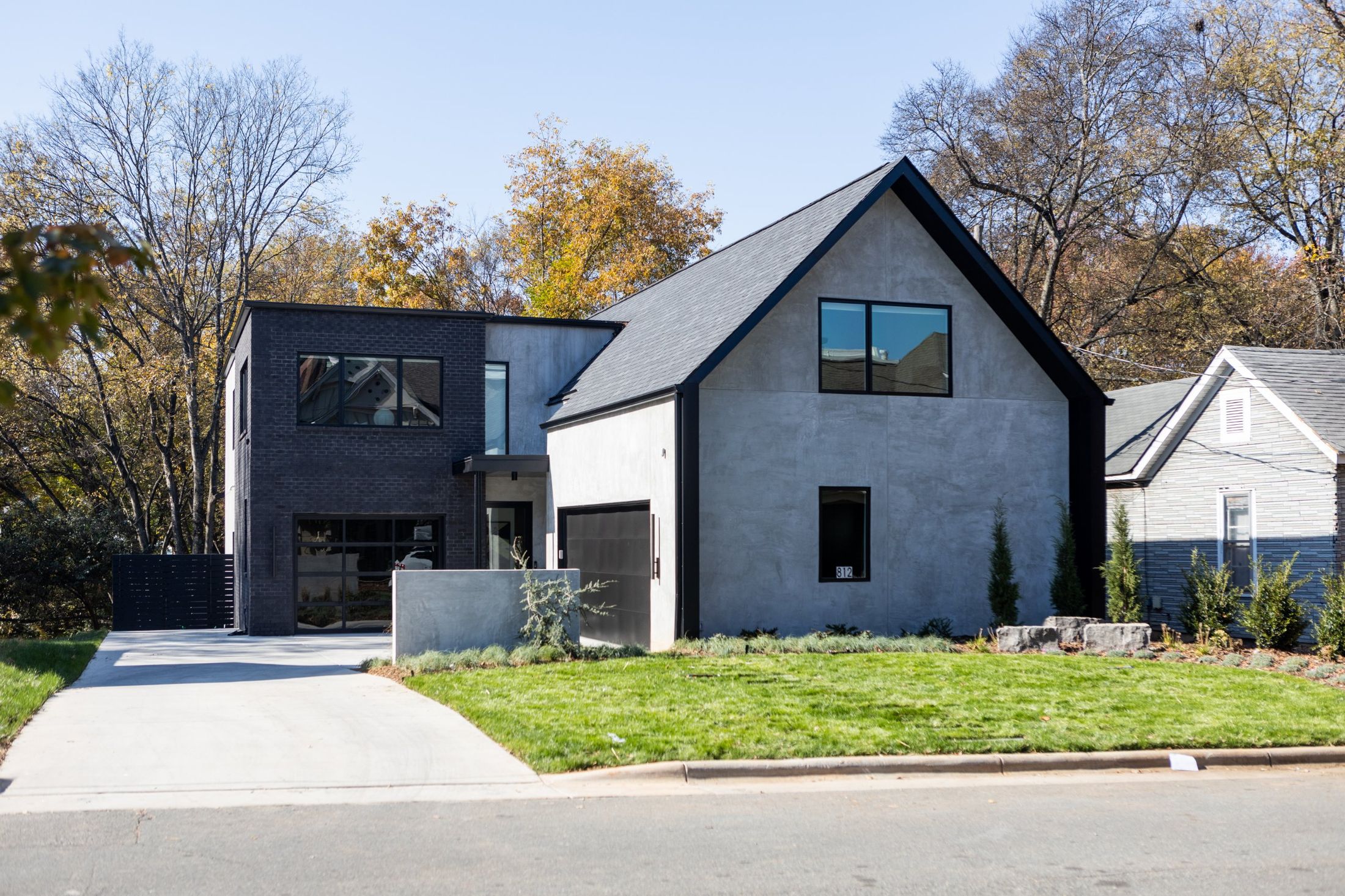 Street view of the gabled concrete and black brick home